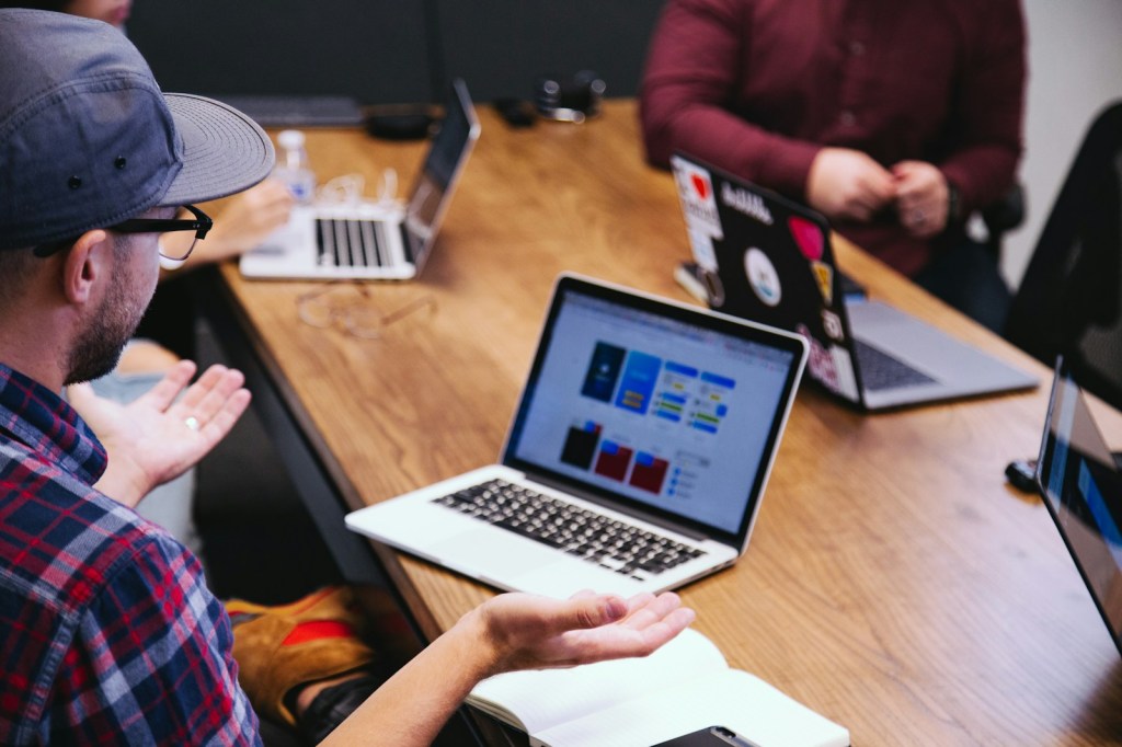 Un gruppo di lavoro discute idee intorno a un tavolo con computer portatili.